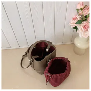 Close-up of stylish bucket bag featuring lychee texture and red drawstring pouch
