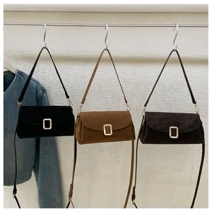 Detail of suede crossbody bags with adjustable straps and vintage gold metal buckles