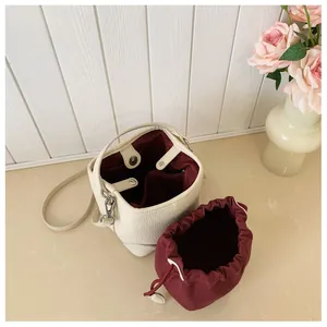 Detail view of cream bucket bag with red drawstring lining and pebbled texture