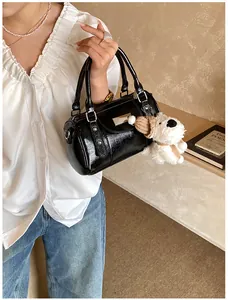 Detail der schwarzen glänzenden Bowlingtasche mit Metallbeschlägen und Plüschwelpen