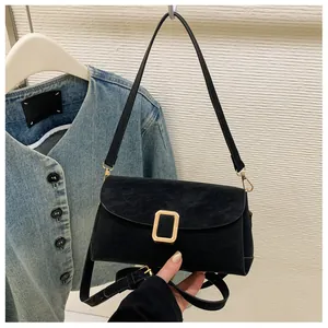 Close-up of black matte flap bag featuring a golden square buckle and adjustable strap