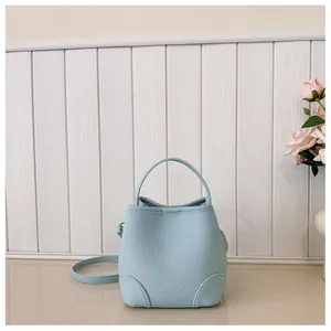Detail of light blue bucket bag showing grainy texture leather and stitching on the base