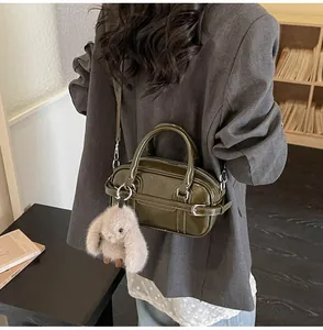 Close-up of olive green glossy bowling bag with silver hardware and plush bunny charm