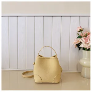 Close-up detail shot of a yellow lychee leather bucket bag with top handle and strap
