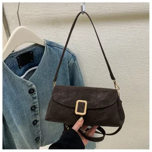 Close-up of a dark brown suede square handbag with a gold metal buckle detail