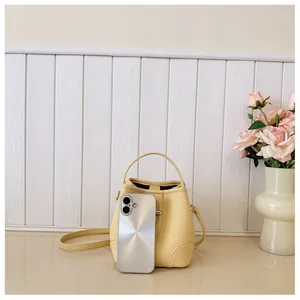 Mini yellow bucket bag with lychee texture shown next to a smartphone for size scale