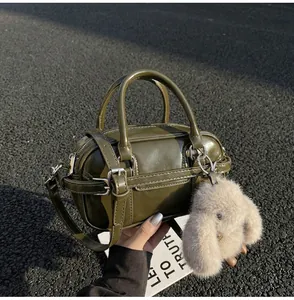 Detailed top view of olive green bowling bag with plush rabbit charm on asphalt background