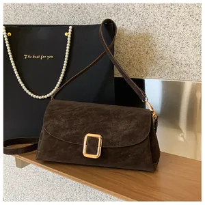 Detail of dark brown suede shoulder bag featuring a rectangular gold metal clasp