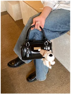 Details einer glänzenden schwarzen Bowling-Tasche mit Silberbeschlägen und weißem Plüschtier