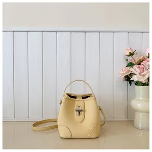 Close-up of cream bucket bag showing lychee grain texture and silver metal twist lock