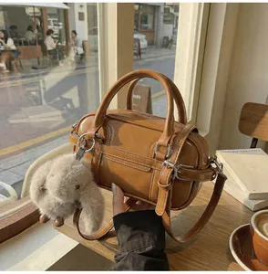 Detail of brown PU leather bowling bag with silver buckles and plush rabbit charm