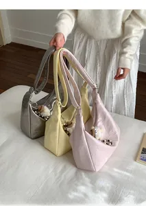 Detailed view of crescent shoulder bags in silver, yellow, and pink with plush pendants