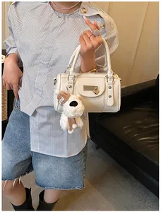 Detailansicht der cremeweißen Tasche mit Herzanhänger und kleinem Plüschhund-Accessoire