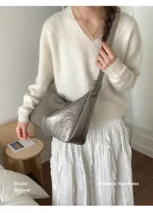 Detail of silver metallic hobo bag featuring glossy crinkled texture and wide shoulder strap