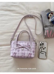 Top view of a purple bucket bag with cat prints, bow detail, and a silver heart pendant
