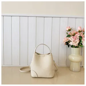 Detailed view of the creamy white bucket bag featuring litchi grain texture and stitching