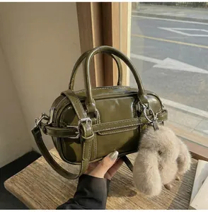 Detail of olive green glossy bowling bag with adjustable strap and plush rabbit charm