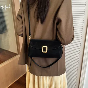 Minimalist black square crossbody bag with gold buckle shown on a model in commute style