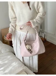 Close-up of pink ruched faux leather shoulder bag with plush pendant and beads
