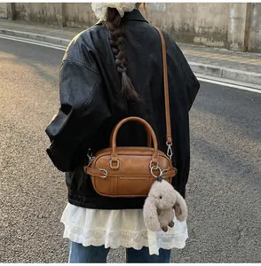 Detail of brown leather Boston bag with plush rabbit charm and adjustable shoulder strap