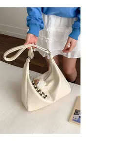 Detail of cream hobo bag with textured leather finish and cute lamb plush charm