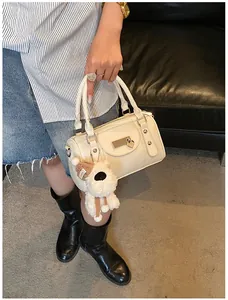 Detail der cremeweißen Bowlingtasche mit Plüschwelpen-Anhänger und Metallherz-Akzent