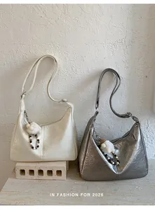 Close-up of semi-moon tote bags in glossy wrinkled leather with plush charms