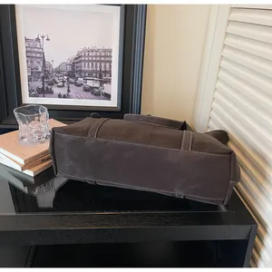 Detail der dunkelbraunen Ledertasche mit weißen Kontrastnähten in Vintage-Atmosphäre