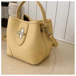 Detailed macro view of yellow lychee grain leather bucket bag with silver twist lock