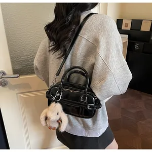 Detail shot of a black glossy bowling bag with a cute plush bunny charm and shoulder strap
