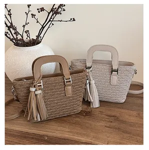 Detail of pleated PU leather bucket bags with tassel charms on a rustic wooden table