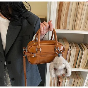 Detail of vintage brown bowling bag with glossy texture and plush rabbit pendant