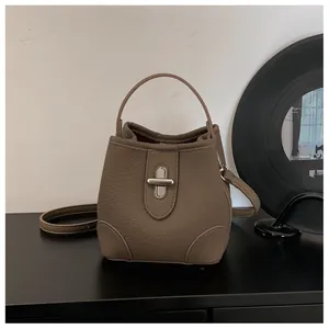Detail of lychee pattern leather bucket bag with silver twist lock and shoulder strap