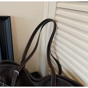 Detail der dunkelbraunen Leder-Tote-Bag mit Kontrastnähten und verstellbarer Silberschnalle