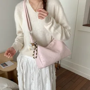 Pink pleated tote bag with plush charm shown on model in a soft minimalist setting