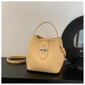 Detail of light yellow lychee grain leather bucket bag with silver metal twist lock