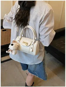 Nahaufnahme der cremeweißen Boston Bag mit Herz-Metallschließe und kleinem Hundeanhänger