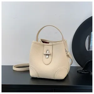Detail of off-white bucket bag featuring lychee grain leather and silver twist lock