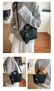 Detail of black woven bucket bag showing silver hardware, tassels and crossbody strap