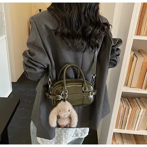 Olive green patent leather bag shown on model with cute plush bunny charm detail