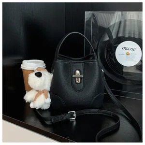 Detail of black lychee leather bucket bag with gold twist lock and adjustable strap