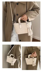 Close-up of cream handbag with quilted fan pattern and sparkling tassel detail