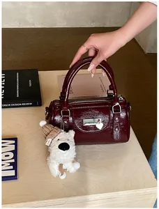 Detail der burgunderroten Lackleder-Bowlingtasche mit Herzanhänger und Plüschhund-Anhänger