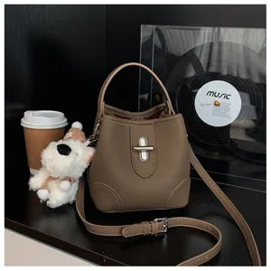Detailed view of a brown pebbled leather bucket bag with silver lock and puppy charm