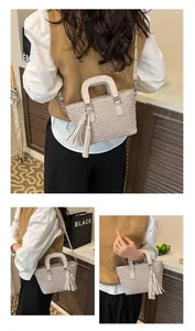 Detailed view of beige monogram bucket bag with tassel ornament and adjustable strap