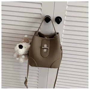 Detail of brown litchi pattern bucket bag with silver lock and plush puppy charm