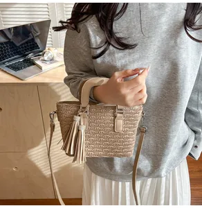 Detail of beige textured bucket bag with scallop embossing and crystal tassel charm