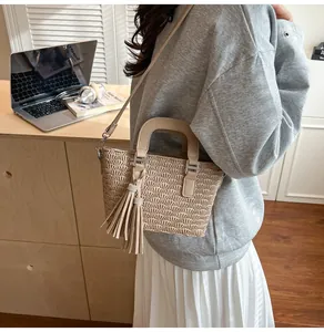 Detail of pleated beige handbag with rhinestone tassel on a minimalist desk