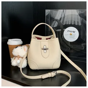 Detail of beige litchi grain leather bucket bag with silver clasp and burgundy lining