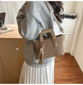 Detail of khaki pleated bucket bag with tassel charm and detachable shoulder strap